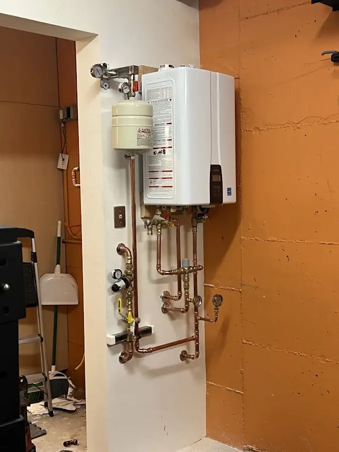 Plumbing technician inspecting water heater connections in Goffstown